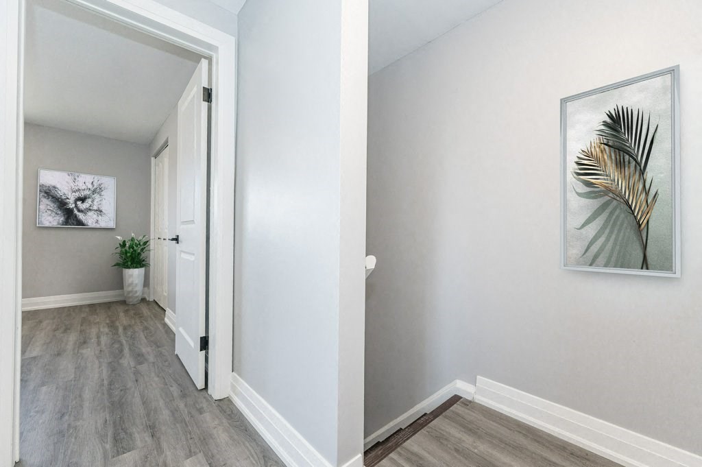 a hallway with white walls and a white door and a plant