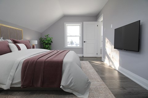 a bedroom with a bed and a tv on the wall