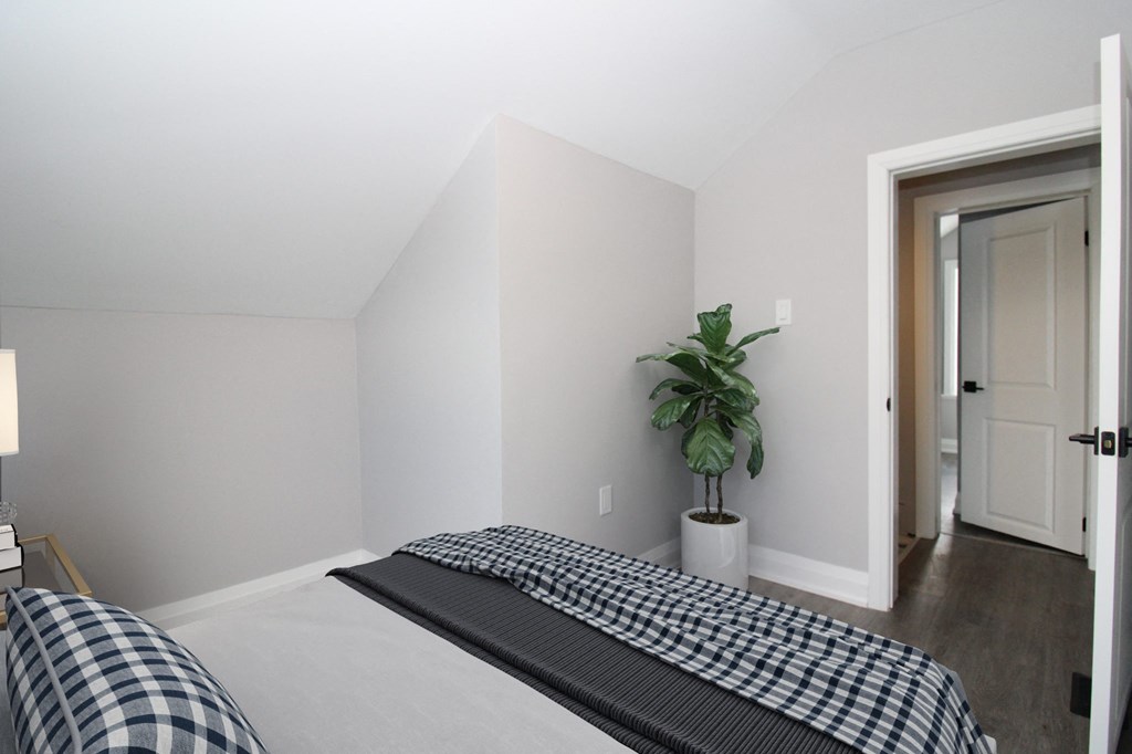 a bedroom with a bed and a potted plant in the corner