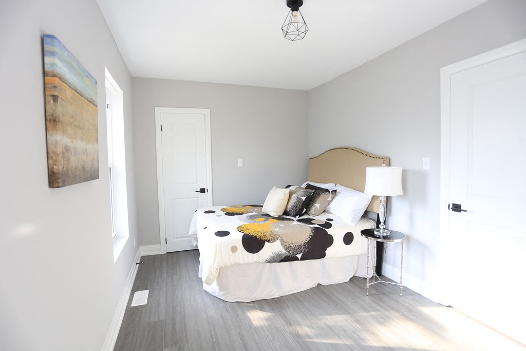 a bedroom with a bed with a white comforter and pillows