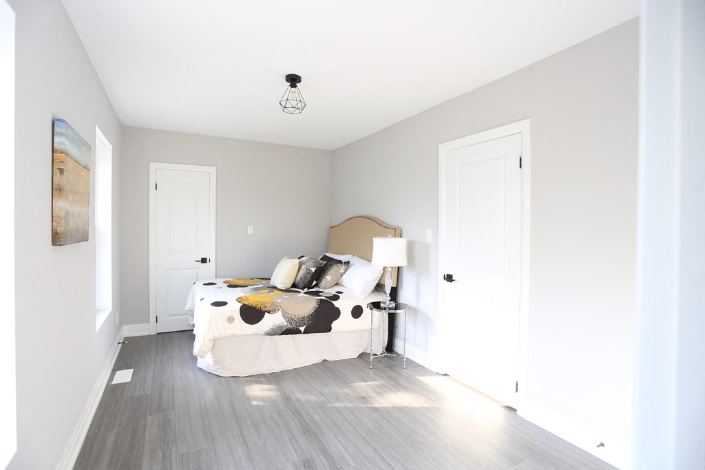 a bedroom with white walls and a bed with a white comforter