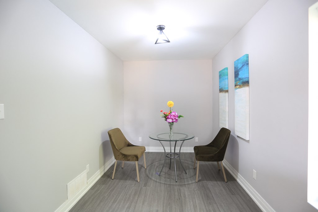 a small dining room with a glass table and two chairs