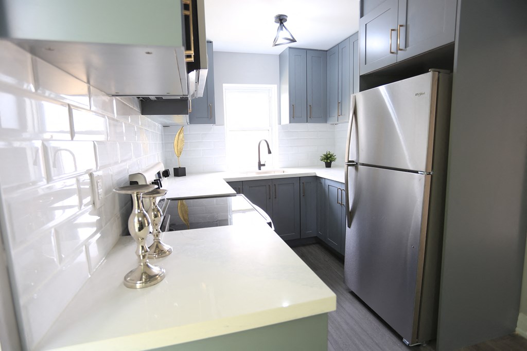 a kitchen with white counter tops and a stainless steel refrigerator