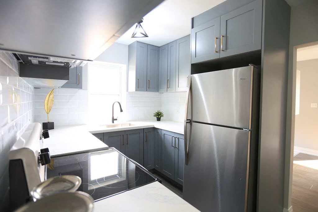 a kitchen with black and white counters and a stainless steel refrigerator