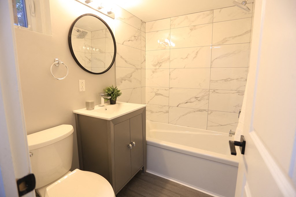 a bathroom with a toilet sink and tub and a mirror