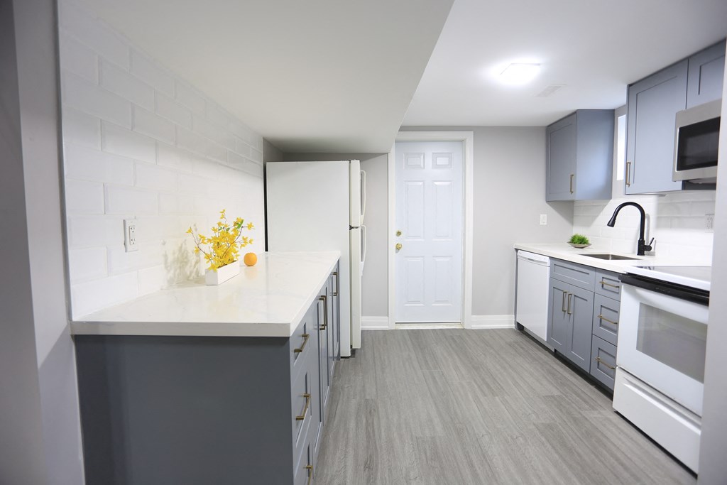 a renovated kitchen with white countertops and gray cabinets