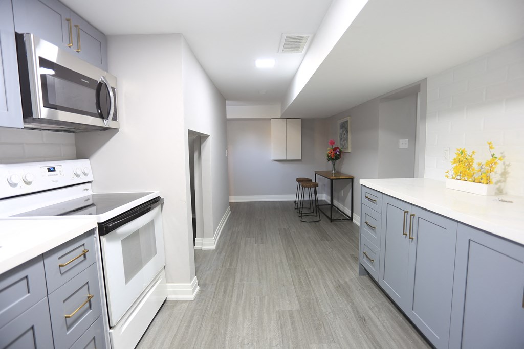 a kitchen and living room with white appliances and gray cabinets
