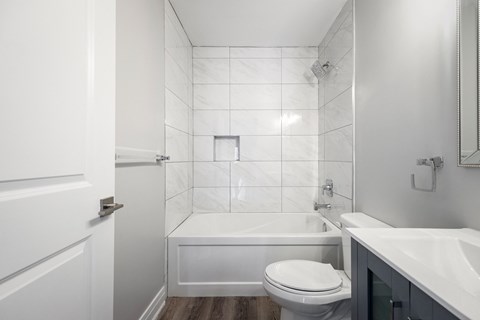 a white bathroom with a toilet and a tub and a sink