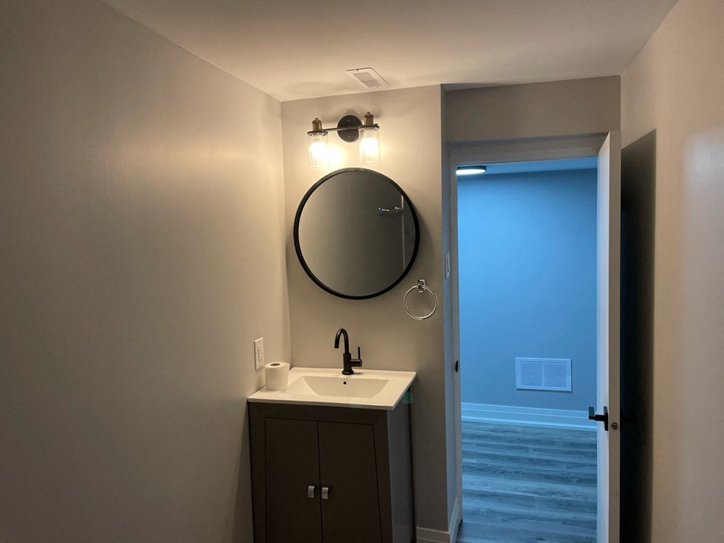 a bathroom with a sink and a mirror and an open door