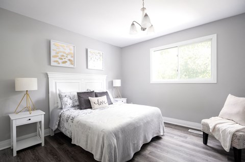 a white bedroom with a bed and a window