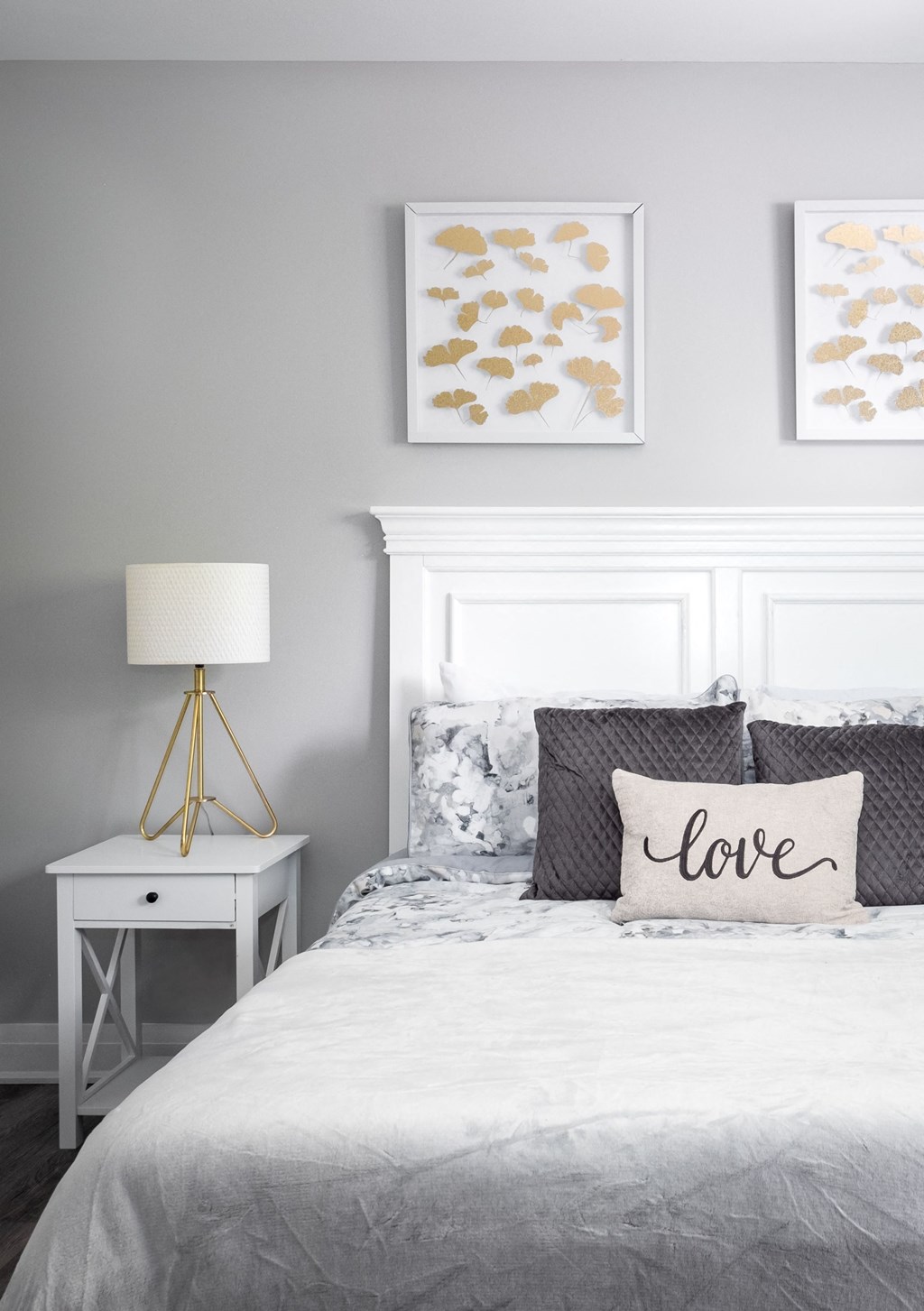 a bedroom with a bed with a white headboard and framed pictures on the wall
