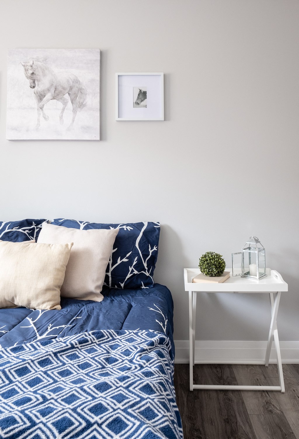 a bedroom with a bed with blue and white bedding and a white side table