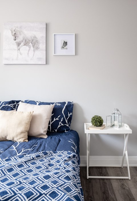 a bedroom with a bed with blue and white bedding and a white side table
