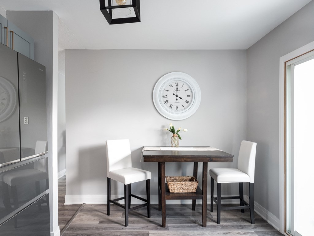 a dining room with a table and chairs and a clock on the wall