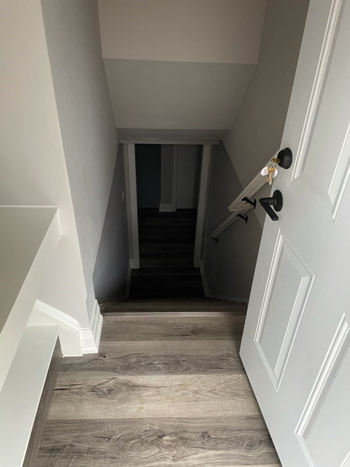 a look down the hallway of a home with white walls and wooden floors