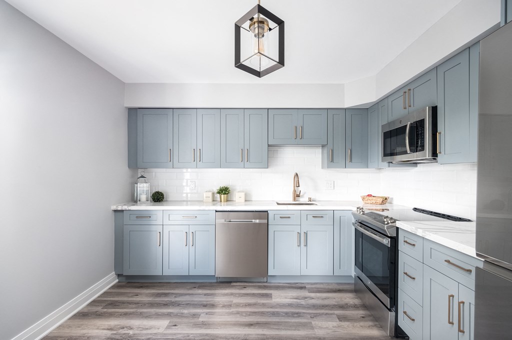 a modern kitchen with blue cabinets and a stainless steel stove and refrigerator