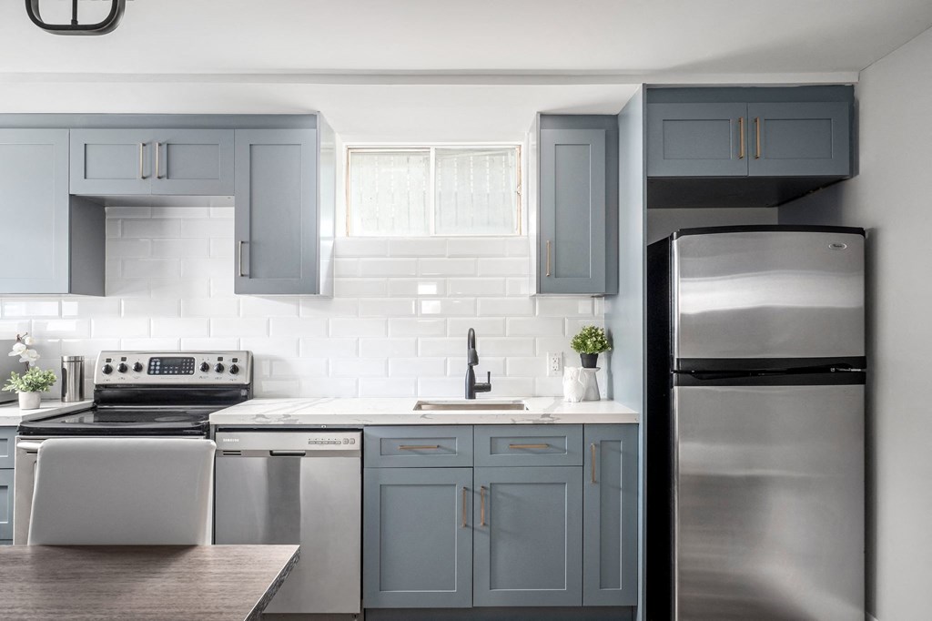 a white kitchen with blue cabinets and stainless steel appliances