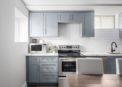 a kitchen with blue cabinets and white appliances and a table and chairs