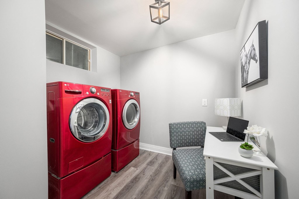 a small room with a washing machine and a desk with a laptop