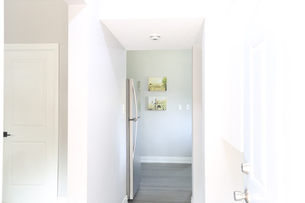 a hallway with white walls and a refrigerator and white door