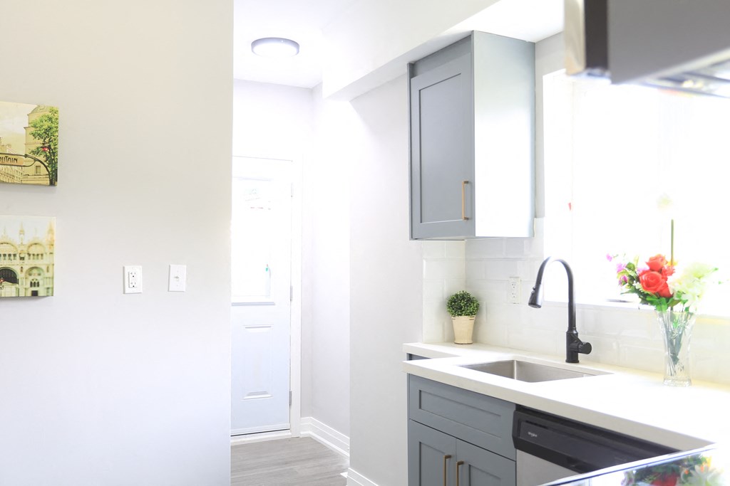 a white kitchen with gray cabinets and a black sink