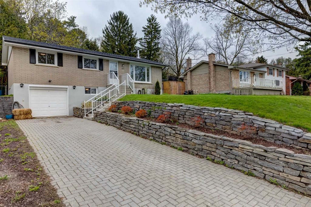 a brick driveway with a stone retaining wall and a house in the background
