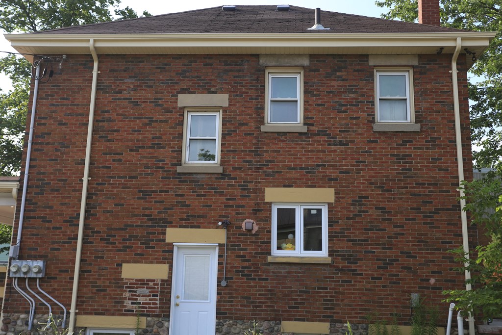 the front of a brick house with a white door and windows