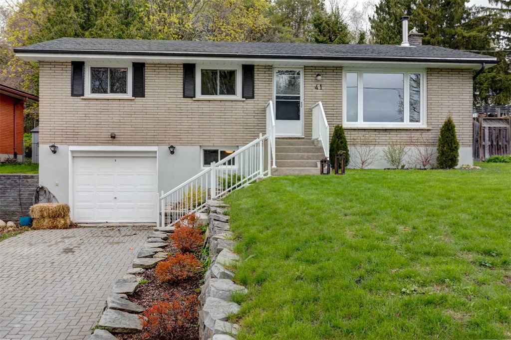 a brick house with a lawn and a white fence