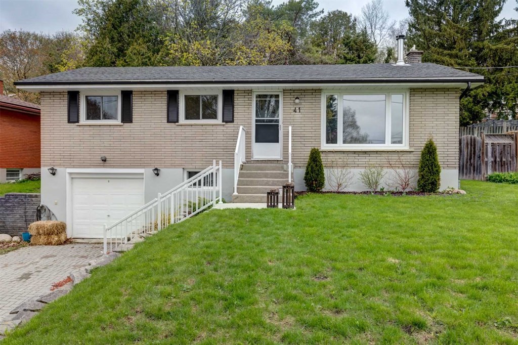 a small brick house with a green lawn and a white porch