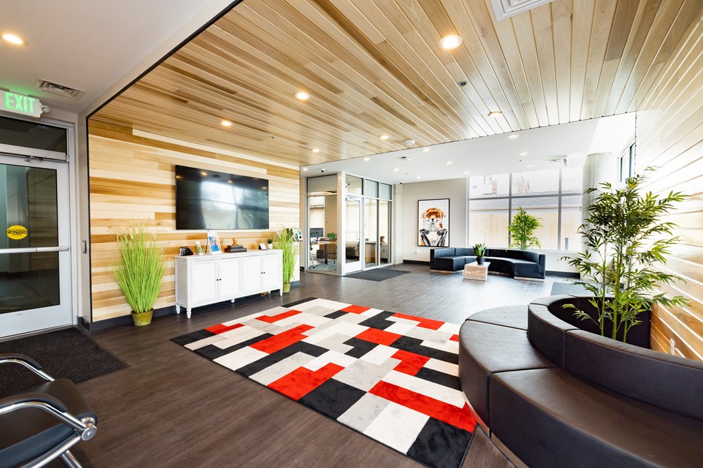 A modern office lobby with a wooden ceiling and a black and white rug.
