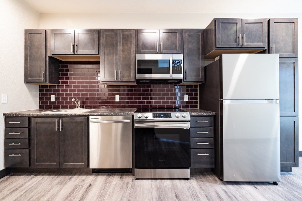 A kitchen with a stainless steel refrigerator, oven, and microwave.