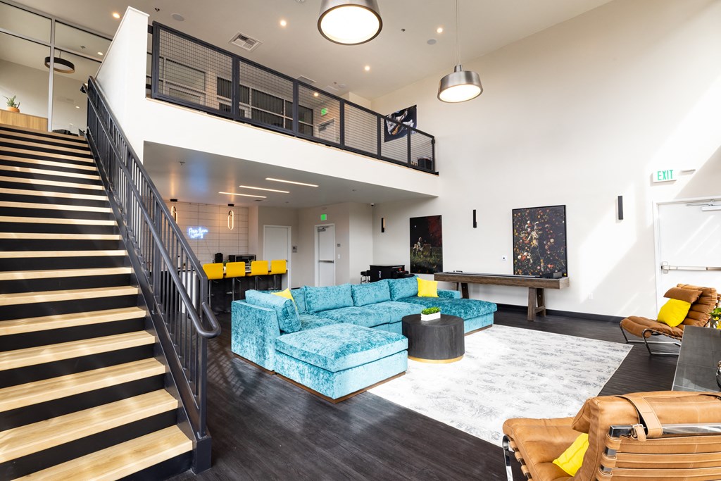 A living room with a staircase and a blue couch.