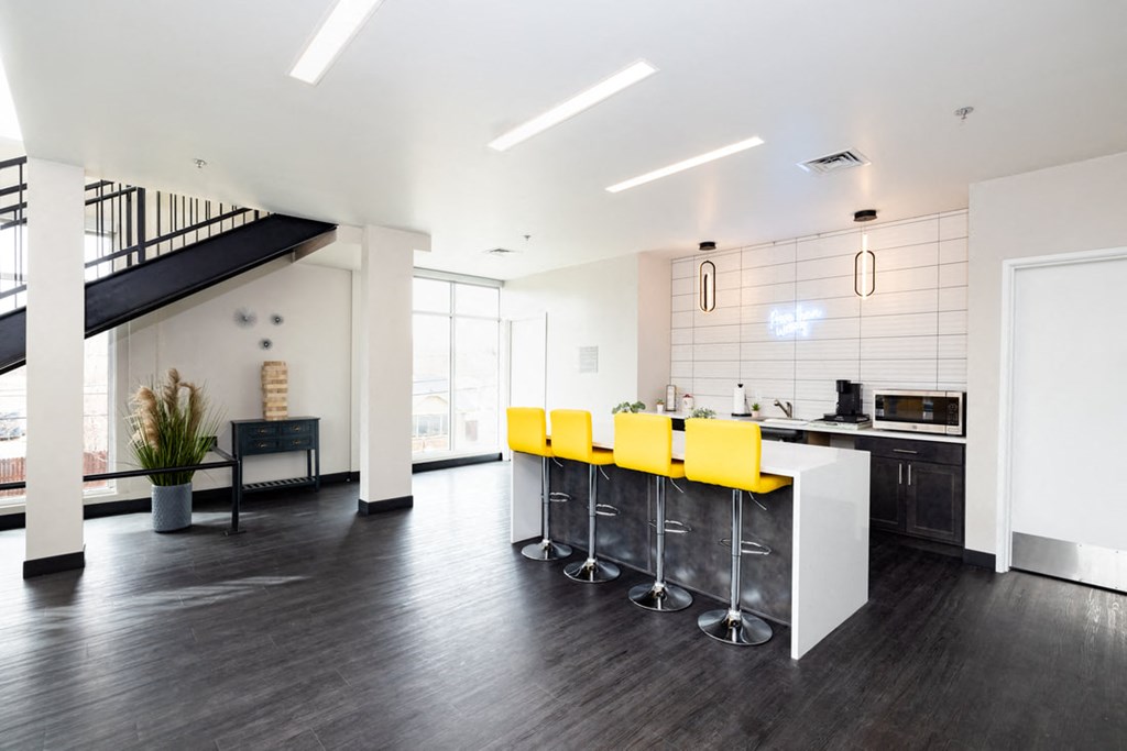 a kitchen with a bar and yellow chairs