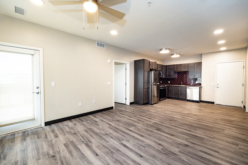the living room and kitchen of a new home with wood floors and a ceiling fan