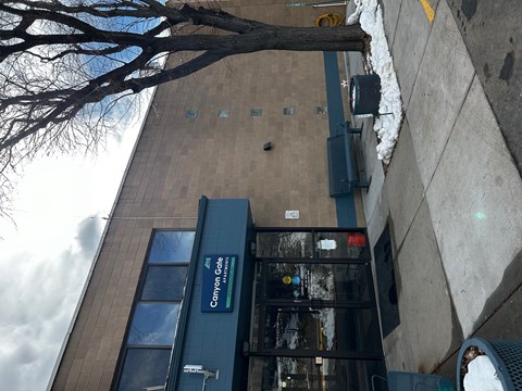 the side of a building with a glass door and a tree
