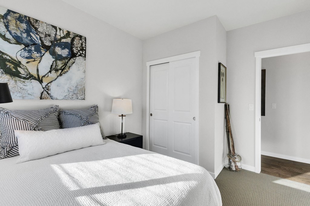 A bedroom with a large bed and a painting on the wall.