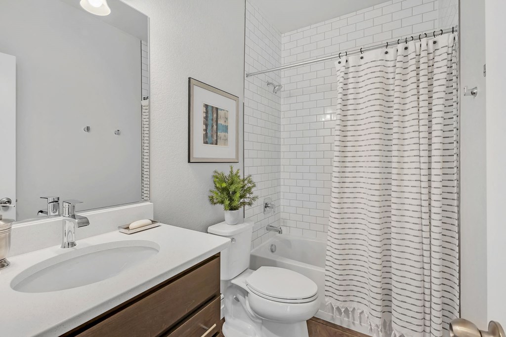 A white bathroom with a white toilet, sink, and shower curtain.