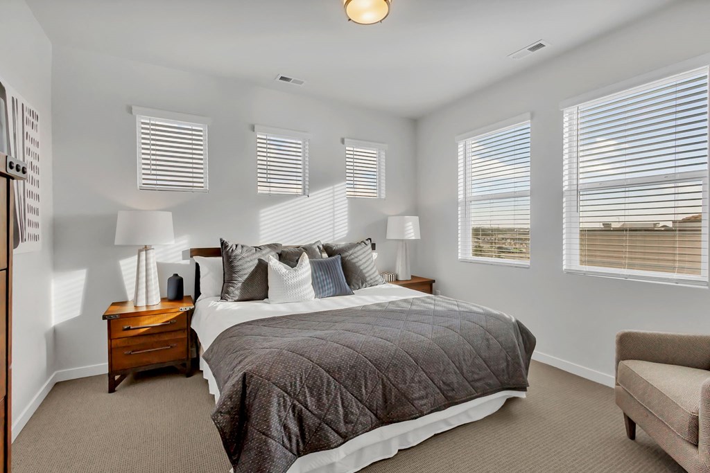 A bedroom with a large bed, a nightstand, and a chair.