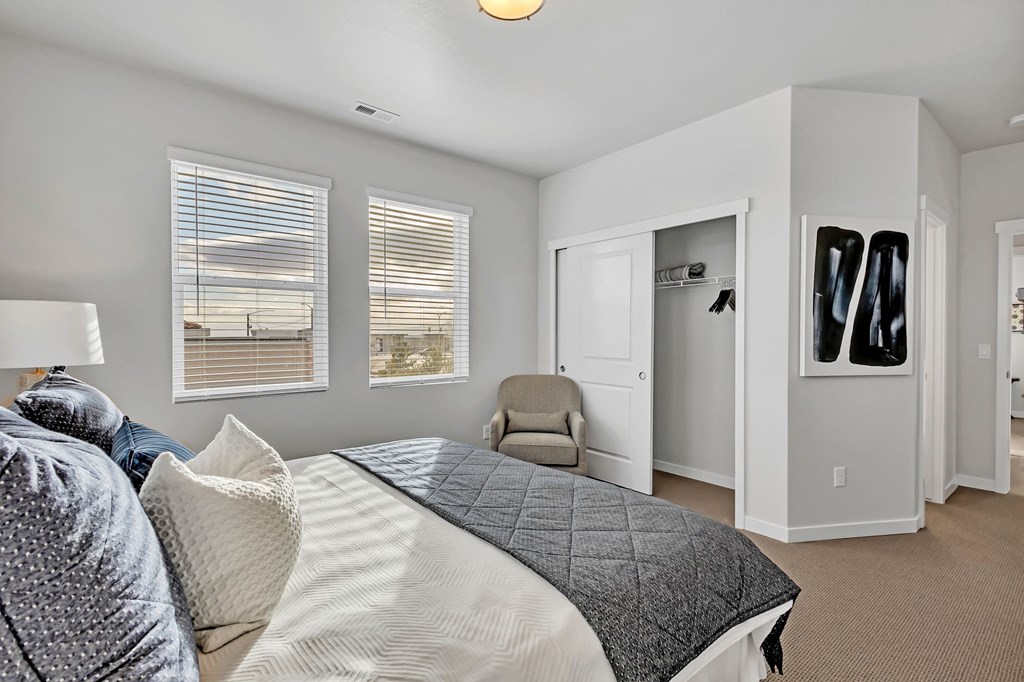 A bedroom with a large bed and a chair.