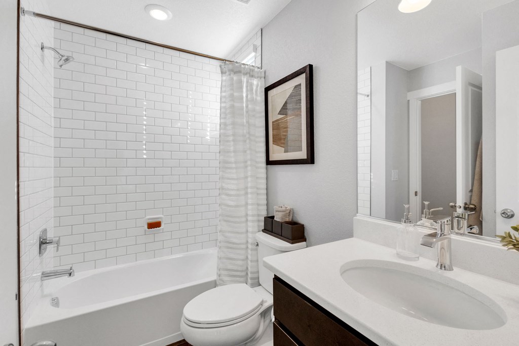 A white toilet is in a bathroom with a white sink and a white bathtub.