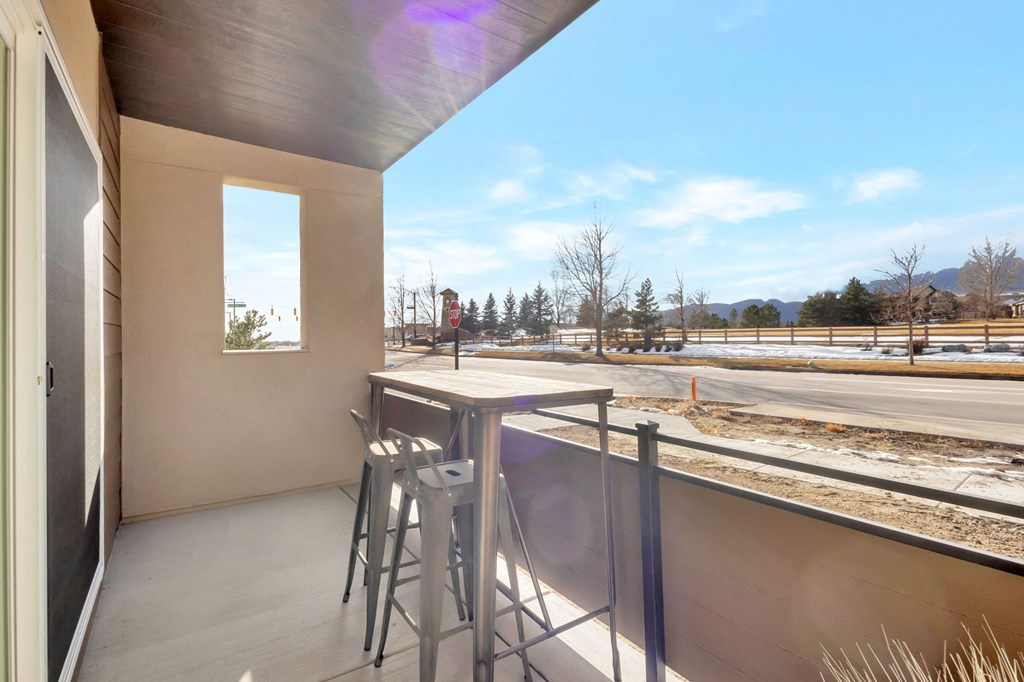 A balcony with a table and chairs overlooking a construction site.
