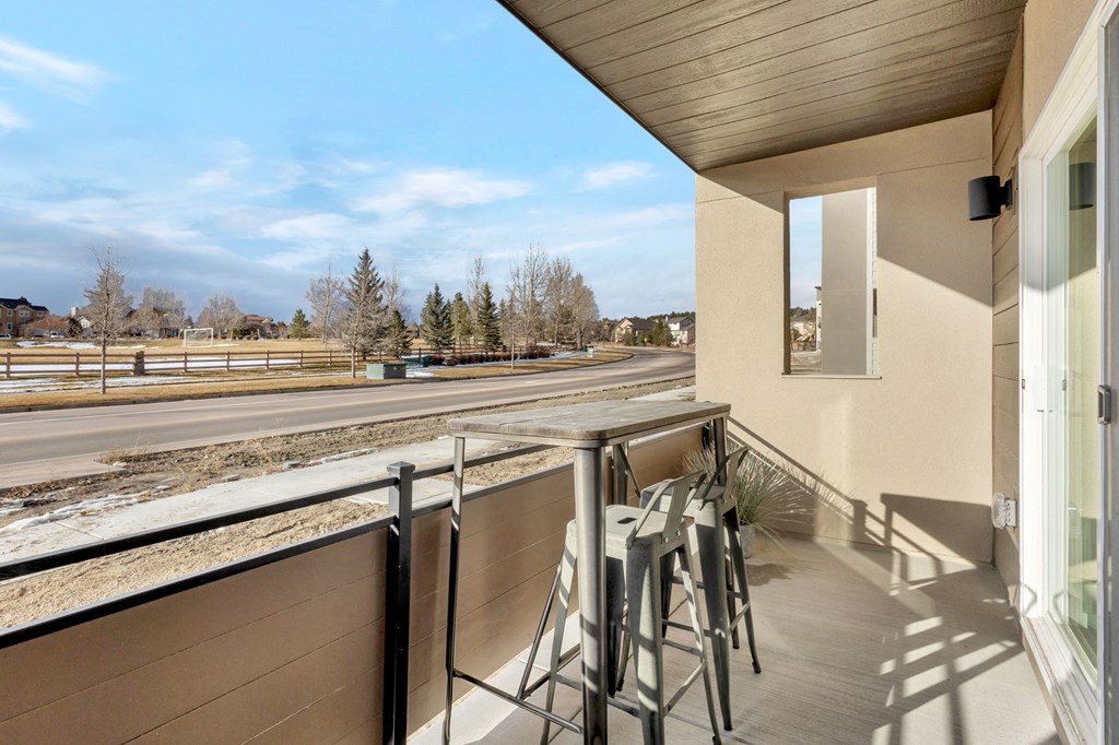 A balcony with a table and chairs overlooking a road.