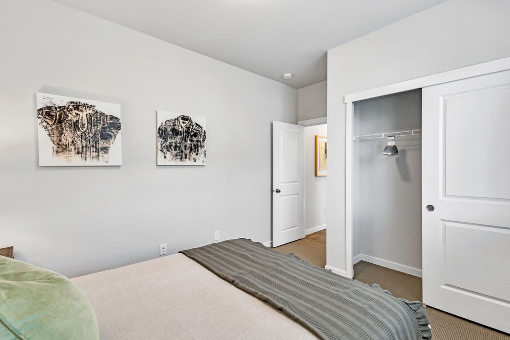 A bedroom with a bed, two paintings on the wall, and a closet.