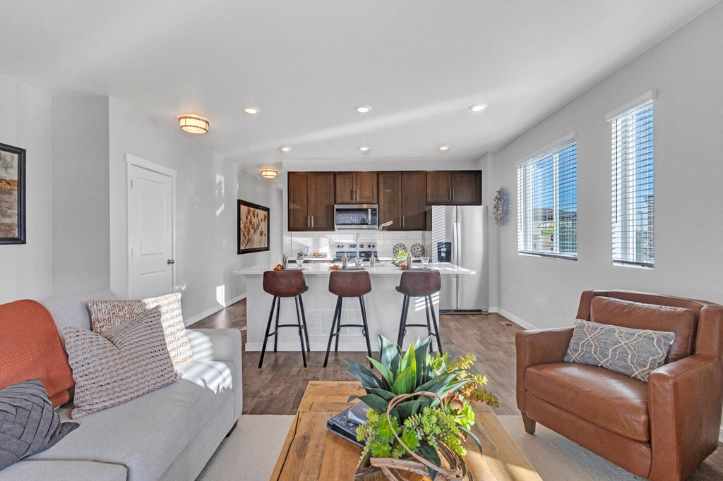 A modern living room with a grey sofa, a brown leather armchair, and a wooden coffee table.