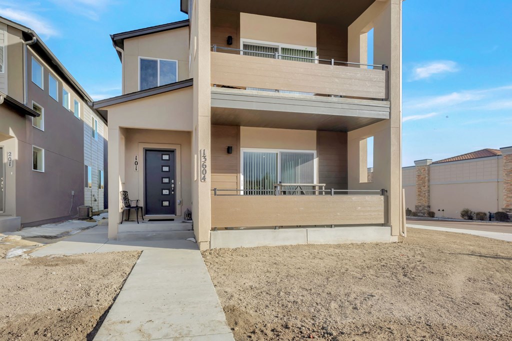 A modern two-story residential building with a balcony on the second floor.