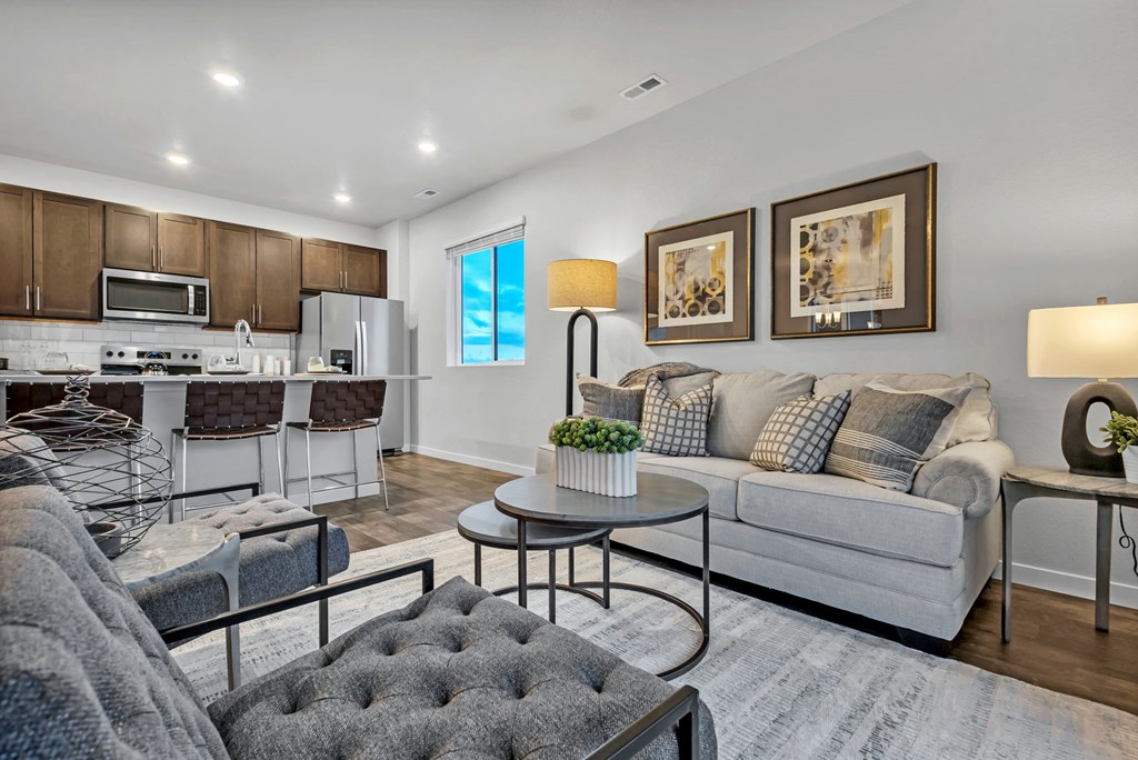 A modern living room with a grey sofa and a grey tufted ottoman.
