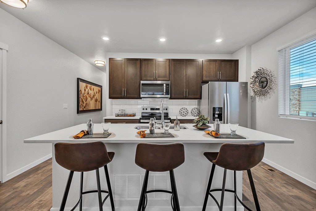 A modern kitchen with white countertops and brown bar stools.