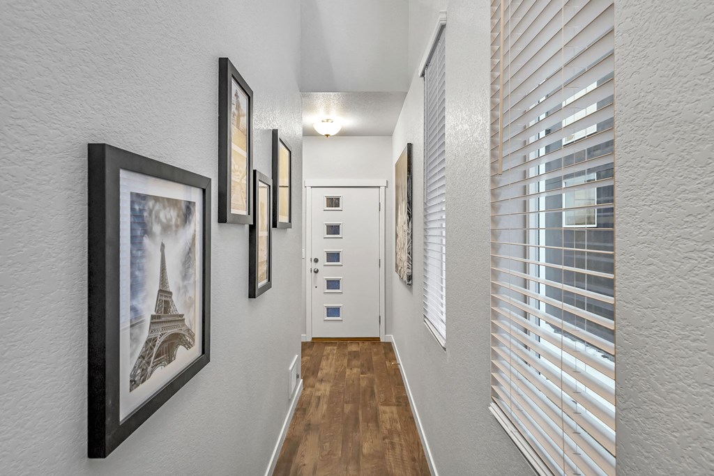 A hallway with a series of pictures on the wall and a door at the end.