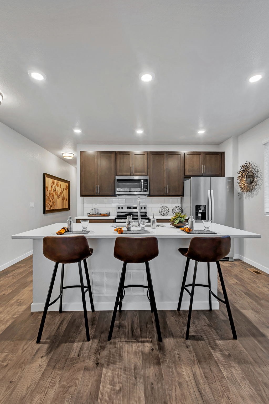 A kitchen with brown bar stools and a white countertop.