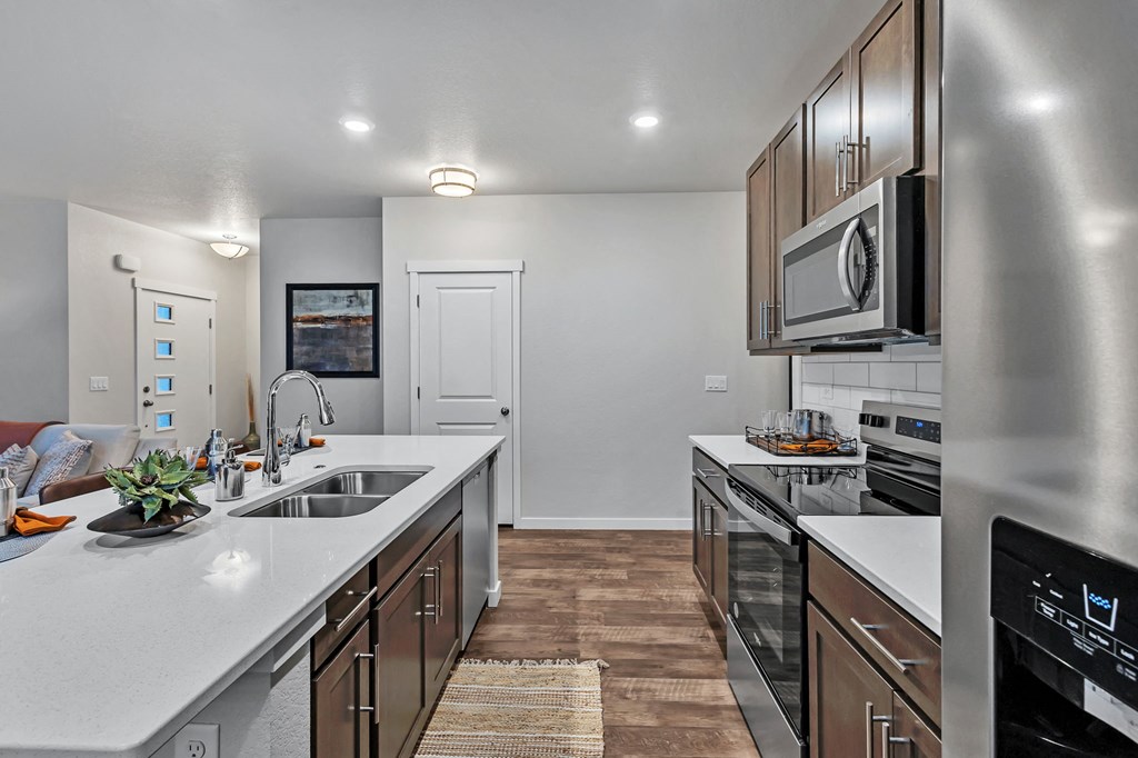 A modern kitchen with stainless steel appliances and wooden flooring.